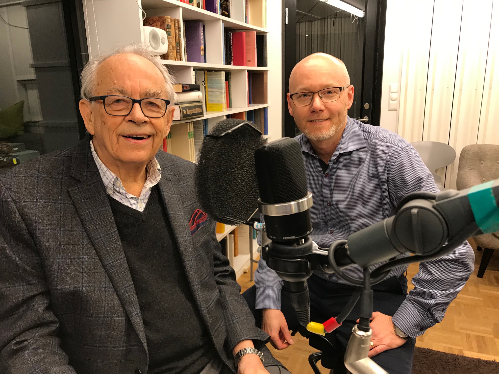 Göran Hydén och Joakim Molander sitter i poddstudion. En mikrofon syns.