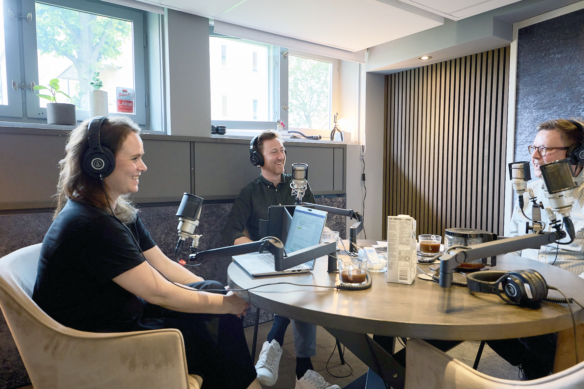 En kvinna och två män i en poddstudio